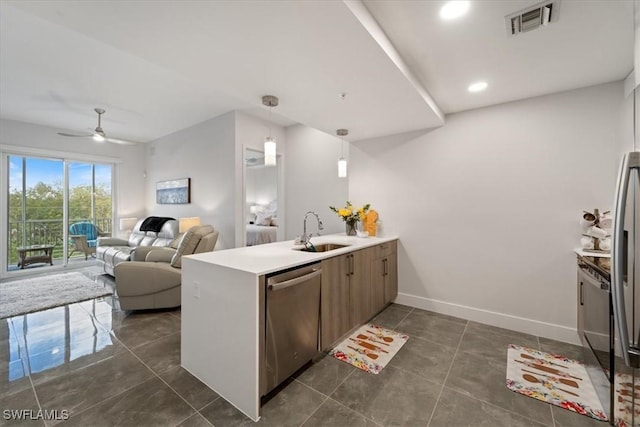 kitchen featuring a peninsula, a sink, visible vents, baseboards, and stainless steel dishwasher