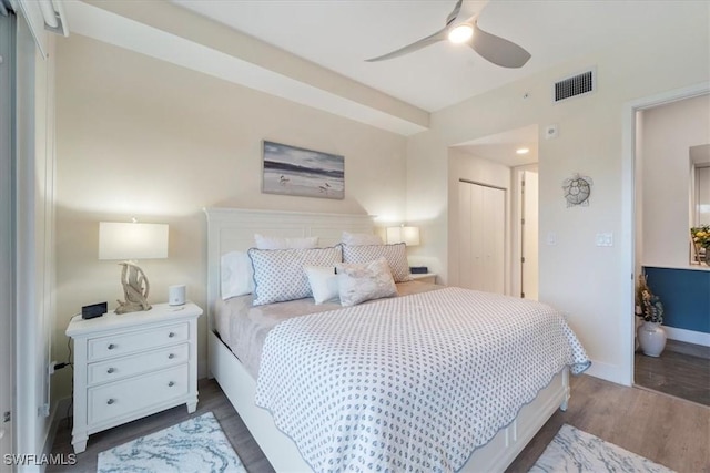 bedroom with ceiling fan, dark wood-type flooring, visible vents, baseboards, and a closet