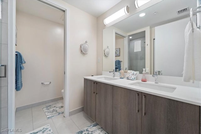 bathroom with toilet, tile patterned flooring, a shower stall, and a sink