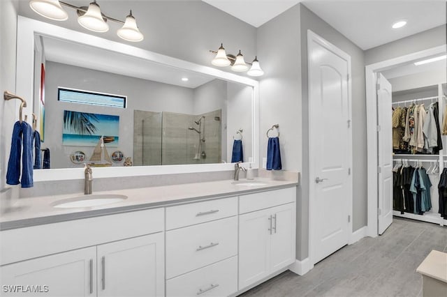 full bath with a stall shower, a sink, a spacious closet, and double vanity