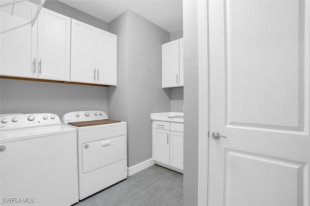 washroom with baseboards, cabinet space, and washer and dryer