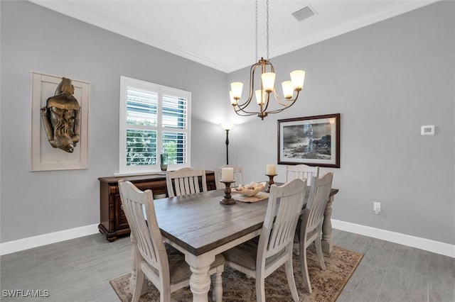 dining space with baseboards, a notable chandelier, visible vents, and crown molding