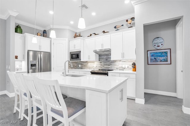 kitchen with visible vents, appliances with stainless steel finishes, crown molding, under cabinet range hood, and a sink