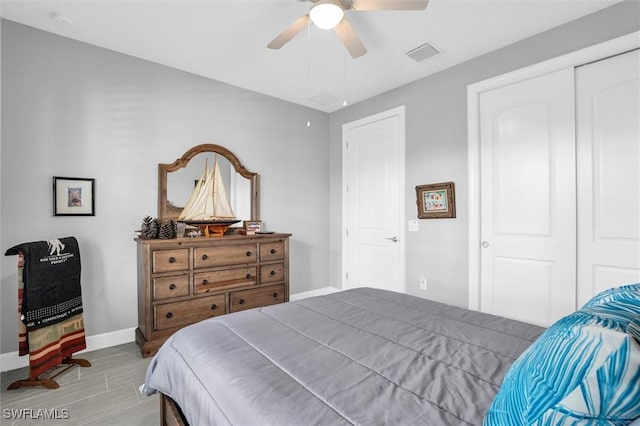 bedroom featuring a ceiling fan, visible vents, baseboards, and wood finished floors