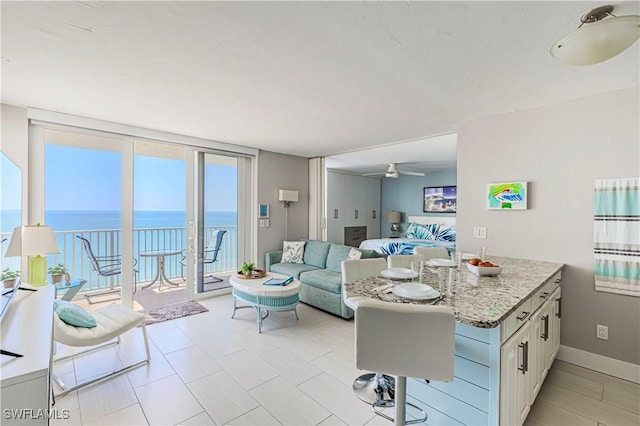 kitchen featuring floor to ceiling windows, a water view, white cabinets, a peninsula, and baseboards