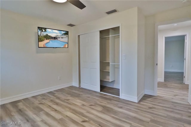 unfurnished bedroom featuring ceiling fan, visible vents, baseboards, light wood-style floors, and a closet