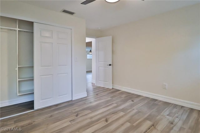 unfurnished bedroom featuring baseboards, a closet, visible vents, and wood finished floors