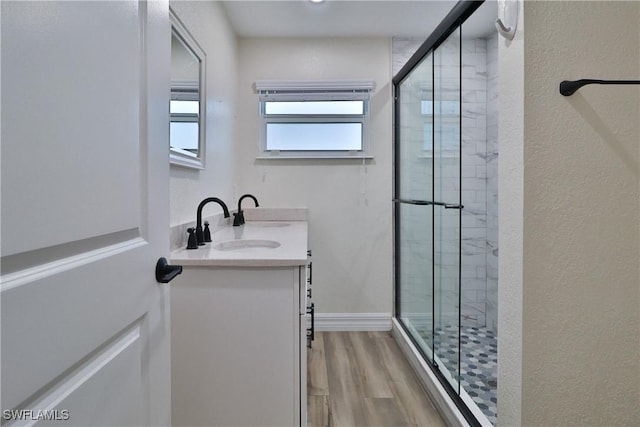 full bath with a shower stall, baseboards, wood finished floors, and vanity