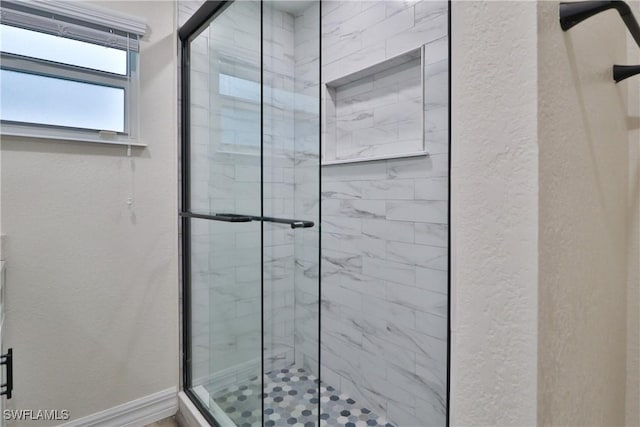 bathroom with a textured wall, a shower stall, and baseboards