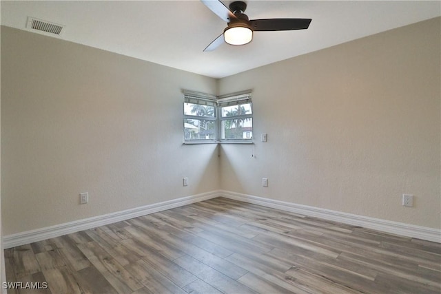 unfurnished room featuring a ceiling fan, wood finished floors, visible vents, and baseboards