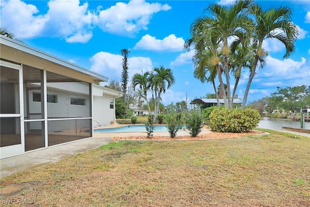 view of yard featuring a sunroom, a water view, and an outdoor pool