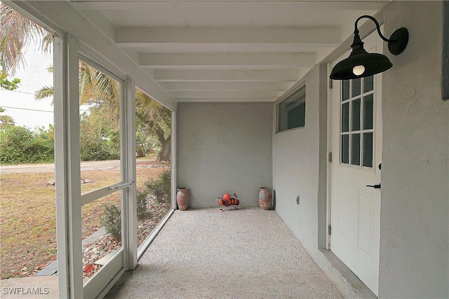 unfurnished sunroom featuring beam ceiling