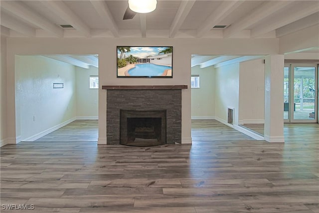 unfurnished living room featuring visible vents, a fireplace, beamed ceiling, and wood finished floors