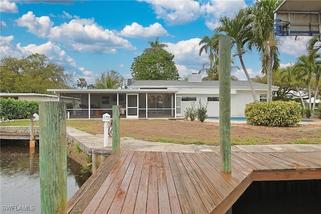 rear view of property with a water view, a sunroom, and a lawn