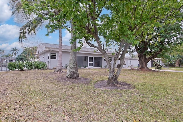 view of front facade featuring a sunroom, a front lawn, and stucco siding