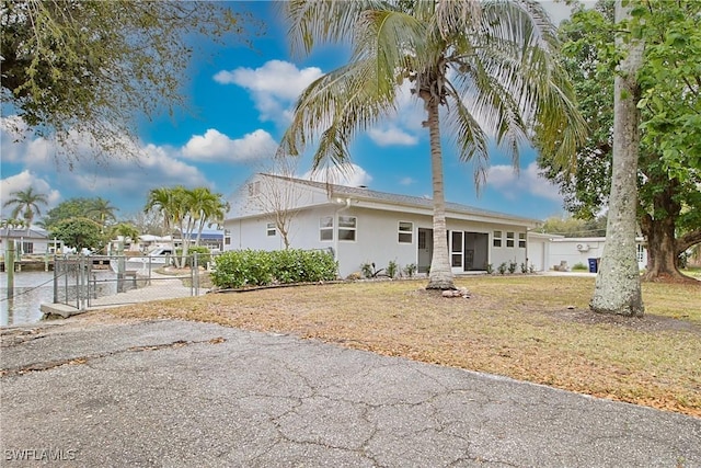 view of front of house with a front lawn, fence, and stucco siding