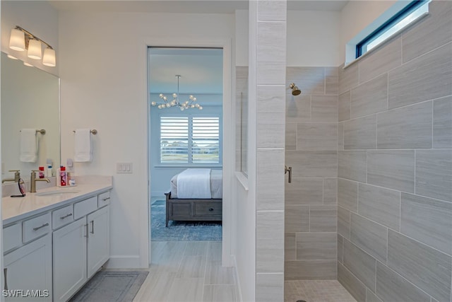 ensuite bathroom featuring a tile shower, vanity, baseboards, and ensuite bathroom