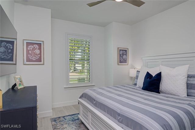 bedroom with light wood-type flooring, ceiling fan, and baseboards