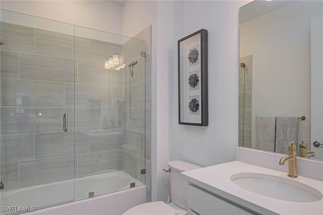 full bath with vanity, toilet, and bath / shower combo with glass door