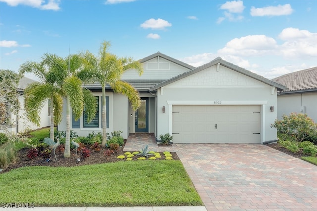 ranch-style house featuring a garage, decorative driveway, a front lawn, and stucco siding