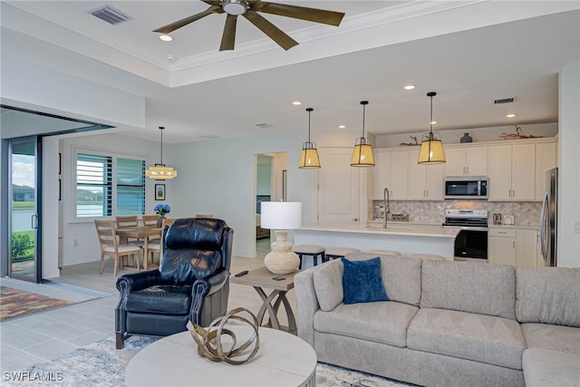 living area with visible vents, a raised ceiling, crown molding, and recessed lighting