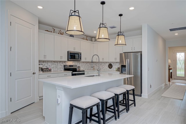 kitchen with light countertops, appliances with stainless steel finishes, a sink, and tasteful backsplash