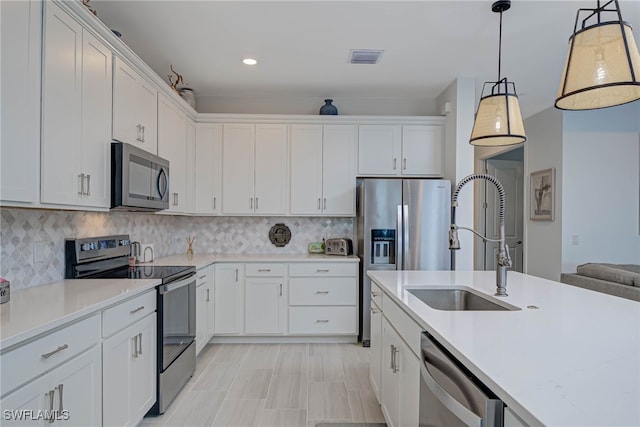 kitchen featuring stainless steel appliances, light countertops, a sink, and white cabinetry