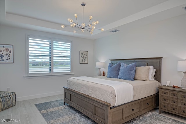 bedroom featuring a chandelier, a tray ceiling, visible vents, and baseboards