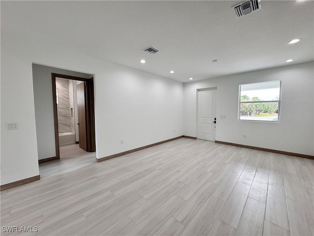 spare room with light wood-type flooring, baseboards, and visible vents