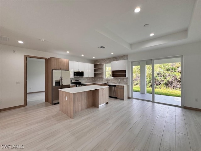 kitchen with open shelves, modern cabinets, a kitchen island, and stainless steel appliances