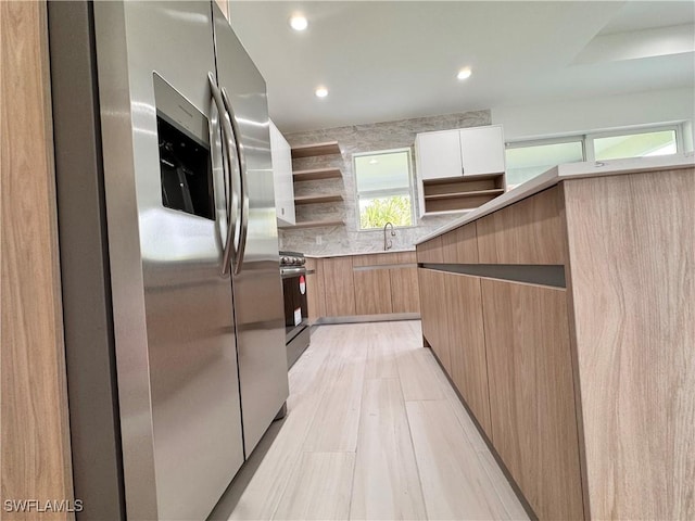 kitchen with light countertops, appliances with stainless steel finishes, open shelves, tasteful backsplash, and modern cabinets