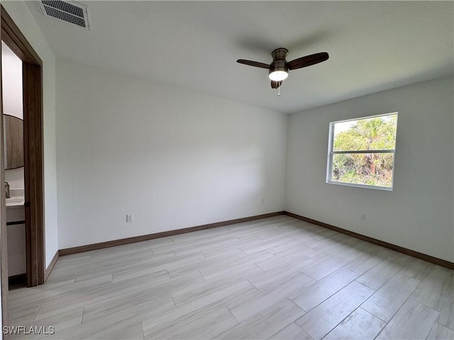 spare room featuring light wood-type flooring, baseboards, visible vents, and a ceiling fan