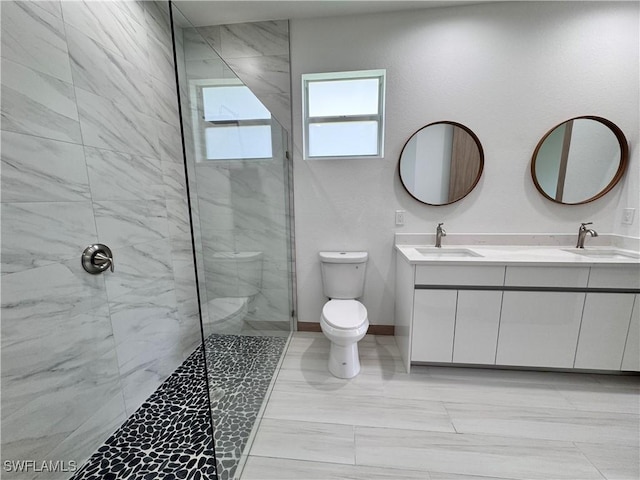 bathroom featuring toilet, a marble finish shower, and a sink