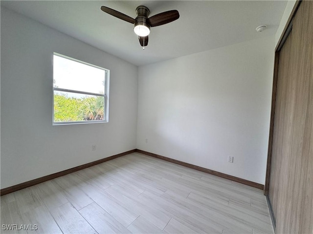 spare room featuring light wood-style floors, ceiling fan, and baseboards