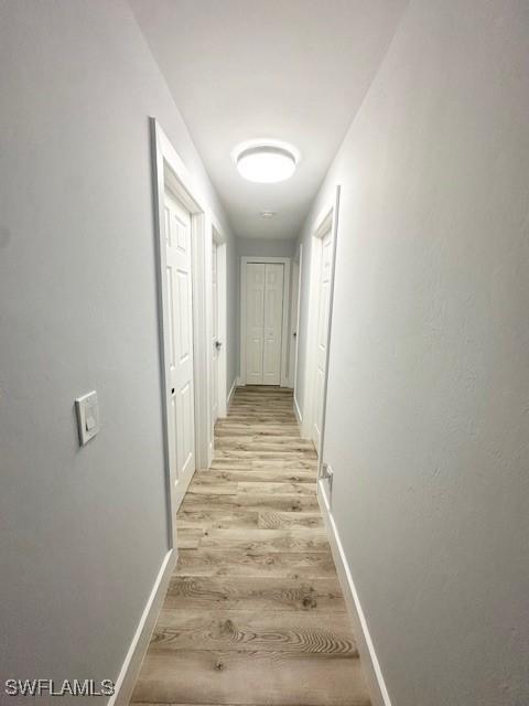 hallway featuring light wood-type flooring and baseboards