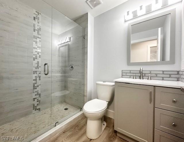 full bath featuring visible vents, toilet, a stall shower, vanity, and wood finished floors