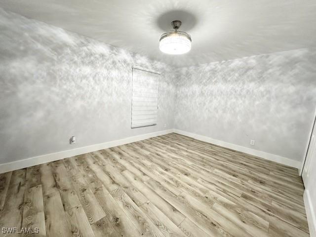 spare room featuring light wood finished floors and baseboards