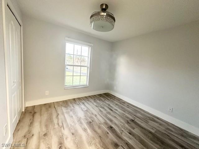 unfurnished bedroom featuring a closet, light wood-style flooring, and baseboards