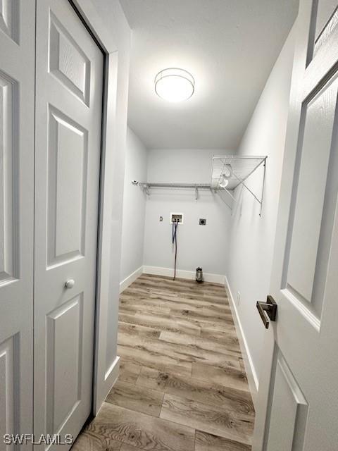 laundry area featuring hookup for a washing machine, laundry area, light wood-style flooring, and baseboards