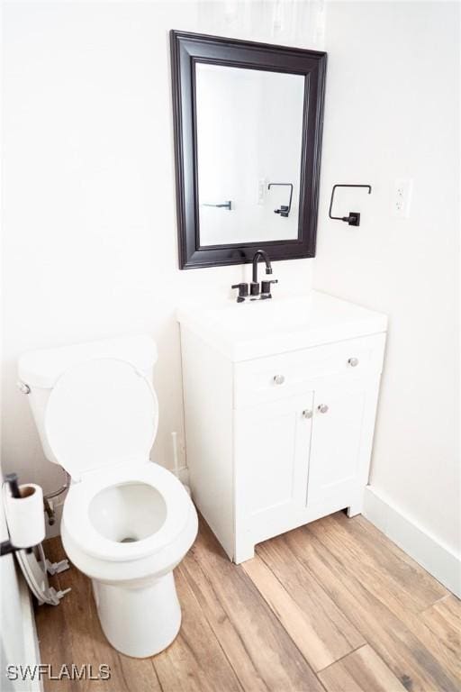 bathroom featuring baseboards, vanity, toilet, and wood finished floors