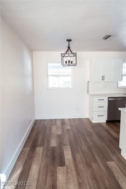 unfurnished dining area with a notable chandelier, baseboards, visible vents, and dark wood-style flooring