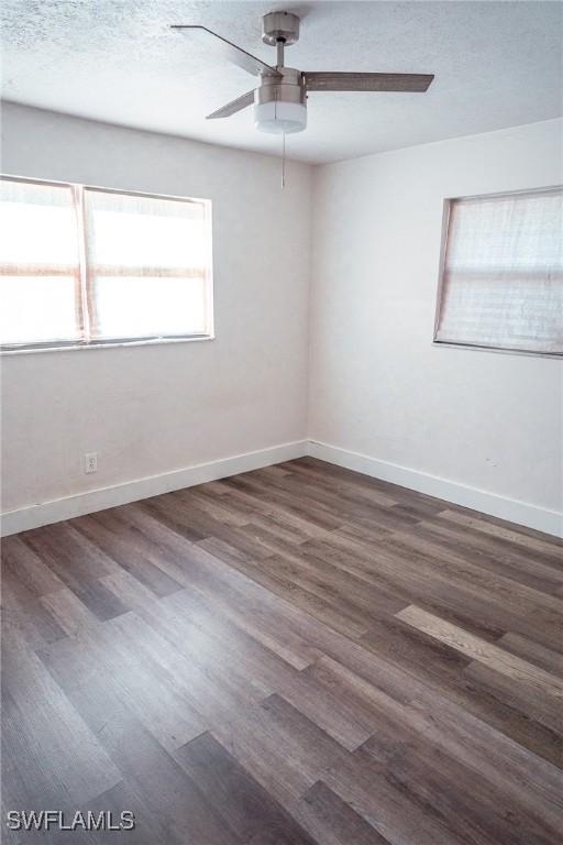 unfurnished room with ceiling fan, a textured ceiling, baseboards, and wood finished floors