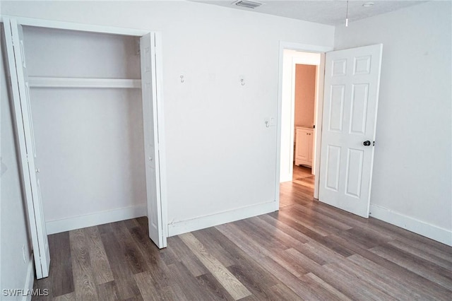 unfurnished bedroom featuring a closet, wood finished floors, and baseboards