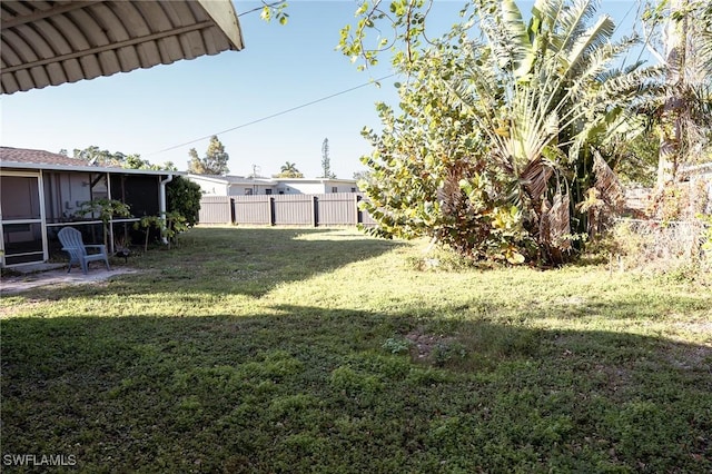 view of yard featuring a sunroom and fence