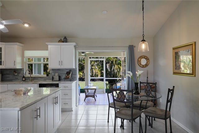 kitchen featuring light tile patterned floors, white cabinets, a ceiling fan, decorative backsplash, and a sink