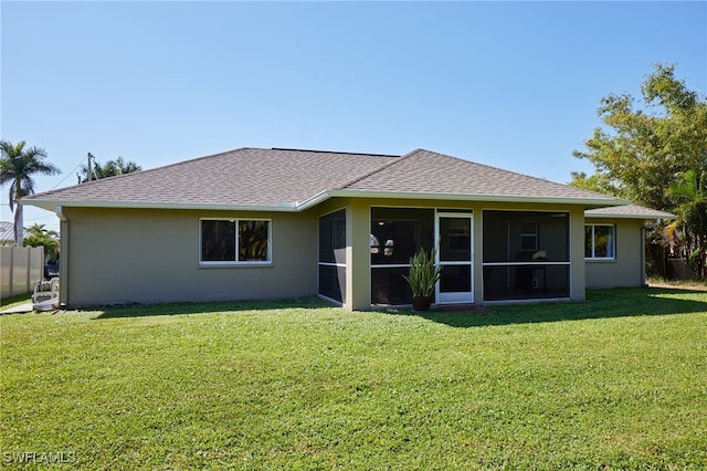 rear view of property featuring fence, a sunroom, a yard, roof with shingles, and stucco siding