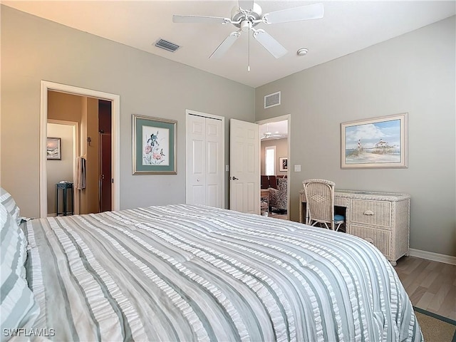 bedroom with a closet, visible vents, baseboards, and wood finished floors