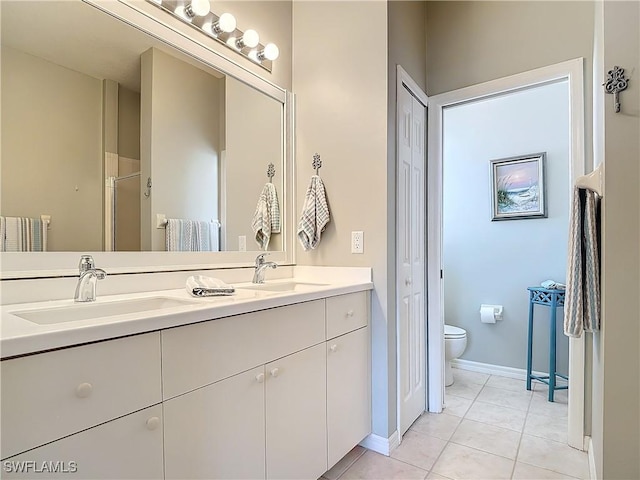 bathroom featuring double vanity, toilet, a sink, and tile patterned floors