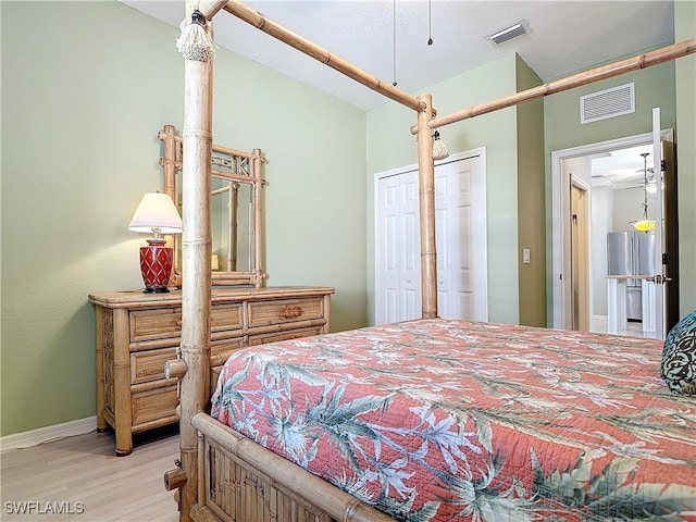 bedroom with light wood-style floors, baseboards, visible vents, and vaulted ceiling