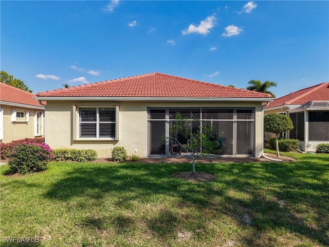 rear view of property with a sunroom, a lawn, and a tiled roof